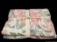 Front view of folded multicolored floral duvet cover with cream band tied around it, showing pink and green tones.