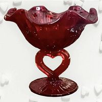 Close-up view of the ruby red footed candy dish featuring the heart-shaped stem and ruffled edge bowl with cabbage rose pattern.