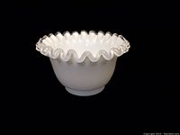 Front view of opaque white milk glass mayo bowl with ruffled silver crest petticoat edge on black background.