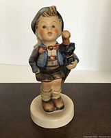 Front view of boy holding umbrella, wearing Bavarian clothing with green cap