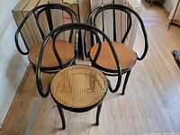 Three black bentwood chairs grouped together on wood floor
