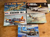 Photo showing four boxed vintage airplane model kits: Airfix B-17G Flying Fortress, Monogram Devastator TBD-1, Monogram Airacobra P-39, and Douglas A-1H Skyraider on wooden surface.
