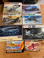 Photo of eight vintage model airplane kits showing brand names, box art, and aircraft types.