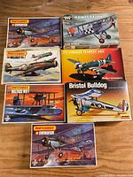 Photo of seven vintage model airplane kits in boxes on wood surface. Includes Matchbox Swordfish (2 versions), Wellesley Mk. I, Walrus Mk. I, Life-Like Hawker Fury, Heller Humbrol Hawker Tempest Mk V, and Lindberg Bristol Bulldog.