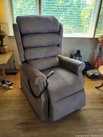 Front three-quarter view of grey fabric electric recliner with remote control