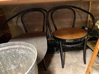 Pair of bentwood chairs side by side against a concrete wall, one with gray fabric seat pad
