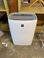 Front view of white RCA portable air conditioner showing housing and power cord connection