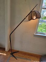 Full view of lamp showing angled teak and metal body with tripod base