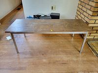 Full side angle view of the rectangular walnut veneer coffee table resting on chrome legs showing the table top and leg structure, placed on wooden floor.