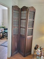 Full view of the three-panel vintage wooden folding screen in room corner.