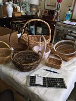 Full view of eight assorted woven baskets on a white cloth.