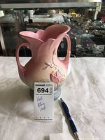 Full view of Hull Pottery double handled vase pink blue with floral relief, with tag and pen for scale.