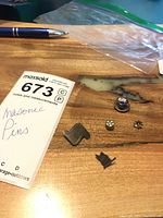 Group of five Masonic pins on wood surface with pen for scale.