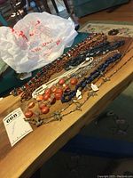 Photo showing seven different necklaces laid out on a wooden table in natural light.