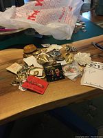 Assorted fashion pins and brooches on a wooden surface with some items in plastic bags and cards.
