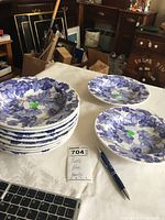 Stack and two single blue ceramic bowls showing grapes and leaves pattern alongside a pen for scale and a paper note with lot details.