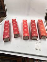 Five red boxed QRS player piano rolls lined up on a white surface.