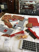 Plastic train garden factory parts arranged on white tablecloth.