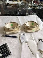 Set of 2 cream soup bowls placed on matching square underplates on white tablecloth with label and pen for scale