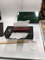 Full view of the stock car model in box with tissue wrapping and foam insert, ruler for size reference, and lot tag in view.