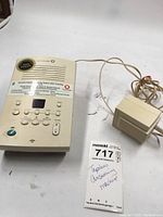 Cream-colored tapeless digital answering machine next to a wired handset with cord. Paperwork partially visible below.