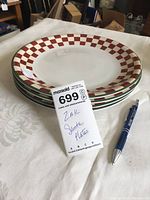 Set of four ceramic dinner plates stacked, showing red and green checkerboard border pattern