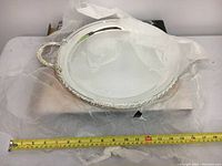 Silver plated round tray with embossed border and handles on tissue paper with measuring tape showing approximately 12 inches diameter.