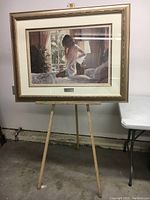Front view of easel holding framed painting, showing overall height and structure
