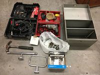 Top view of all items in lot including two drills in cases, hardware box, plastic bag of screws, hammer and bathroom fixtures