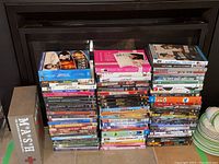 Overall view of the DVD lot stacked in three piles with various movie and series titles visible including a boxed M*A*S*H collection.