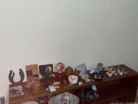 Wide shot showing all items arranged on wooden furniture including horseshoes, teapots, plaques, geodes, and figurines.