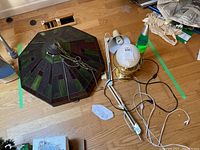 Overview of the four lamps including the hanging stained glass fixture, the adjustable lamp, the globe lamp, and the lava lamp on a hardwood floor.