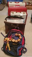 Lot contents showing all luggage pieces, briefcase, backpack, and massager arrangement on floor
