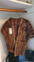 Full view of the mink fur stole hanging on a wooden hanger.