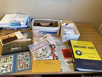 Overview of all stamps, albums, loose stamps, and boxes laid out on a table.