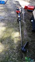 Full length photo of Echo SRM22S string trimmer laid on ground showing the straight shaft, loop handle, engine, and cutting head with guard.