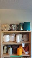 Overall view of multiple cones and skeins of thread and yarn on wooden shelves showing various colors and sizes.