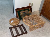 Photo showing wooden chip and dip bowl, small dark wood rack, collapsible wicker wall shelf and two decorative serving trays leaning against wall.
