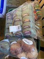 Plastic bag containing multiple skeins of light green Jo Sharp wool yarn with labels visible
