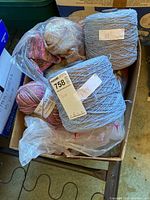 Photo showing box with cones and skeins plus a plastic bag with knitting/crochet projects inside.