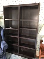 Full front view of the brown wooden bookcase showing adjustable shelves and wear.