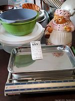 Mrs. Tiggy Winkle ceramic cookie jar, green and gray plastic mixing bowls, Rubbermaid container with lid, and Krups Classic kitchen scale metal platform with blue scale markings.