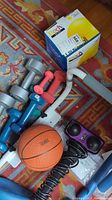 Photo showing assorted dumbbells, orange basketball, electric massage stick handle and fitness ball box