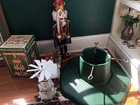 Photo of the German Christmas pyramid, nutcracker, tree stand and box of party crackers on a wooden floor next to a blue wall.