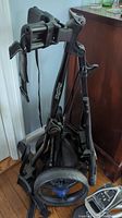 Folded view of Bagboy Express DLXPro golf bag caddy showing black metal frame and straps.