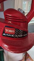 Close-up of Toro branding on red plastic housing with model name Rake and Vac visible.