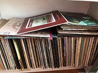 Photo showing two shelves filled with worn classical vinyl LP albums in jackets, some with visible wear and discoloration.