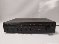 Front view of the Harman Kardon HK385i stereo receiver showing power control, volume and tuning knobs, input selector, and AM/FM frequency display.