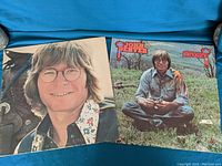 Two vinyl albums by John Denver including 'John Denver' and 'Spirit' covers visible
