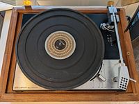 Overhead view of turntable mounted in wooden plinth showing platter, tonearm and control panel.